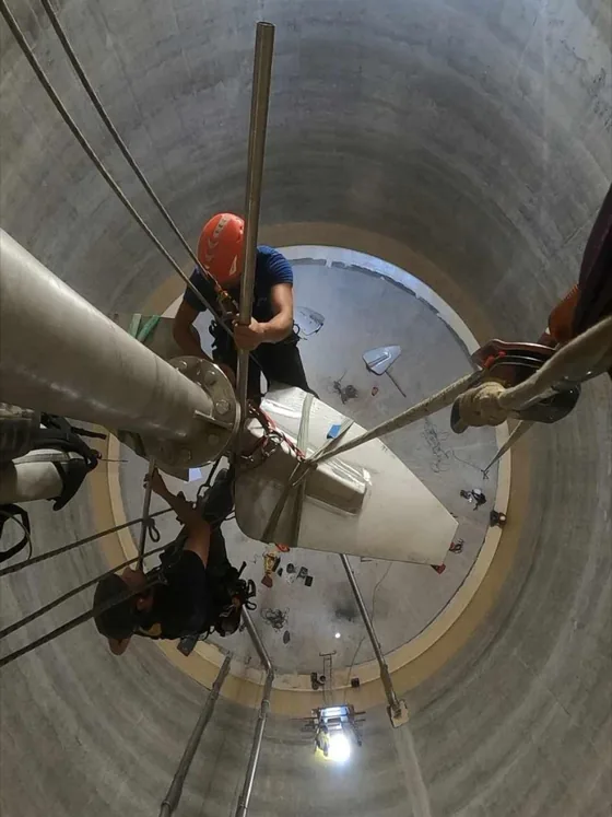 Cordistes déplaçant une pièce industrielle à l'intérieur d'un ouvrage cylindrique