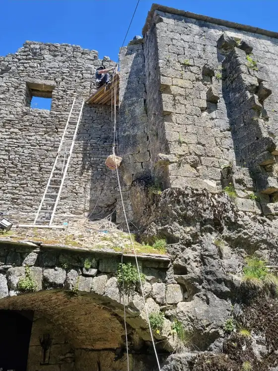 Cordiste en reprise de maçonnerie sur un mur de pierre en hauteur