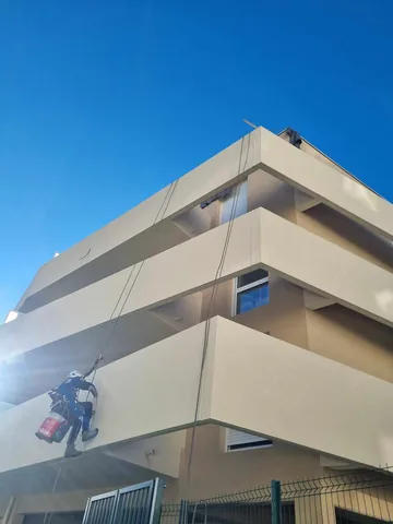 Cordiste en descente le long de la façade d'un immeuble moderne
